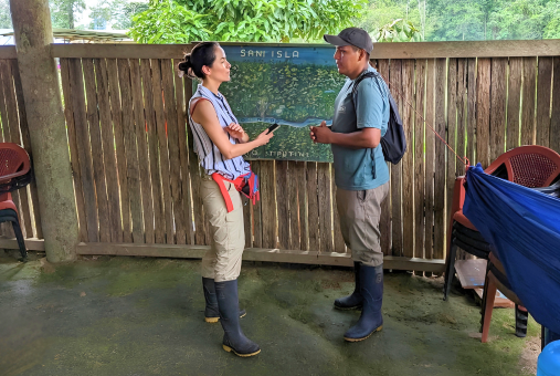 Two people having a conversation in a rustic shelter with a map on the wall.