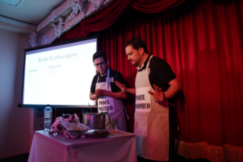 Two men in aprons on stage in front of a screen