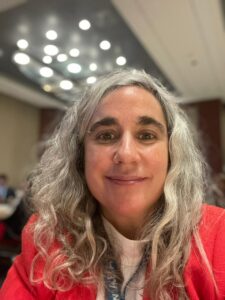 Mujer de mediana edad cabello cano mirando sonriendo a la cámara.