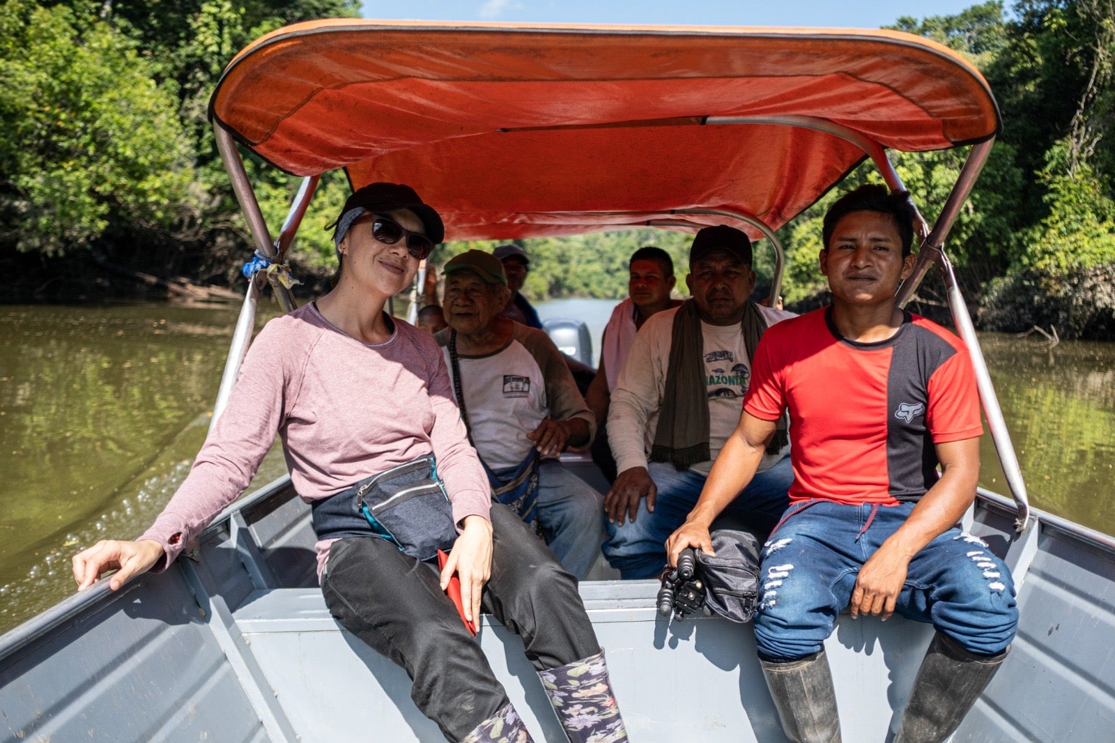 A group of people traveling on a boat through a river, surrounded by lush greenery.