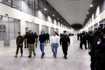 President Nayib Bukele walks with top security and government officials inside El Salvador’s high-security Terrorism Confinement Center (CECOT), flanked by rows of heavily armed police officers.