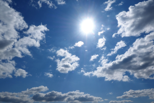 Sun burning bright in a blue cloudy sky