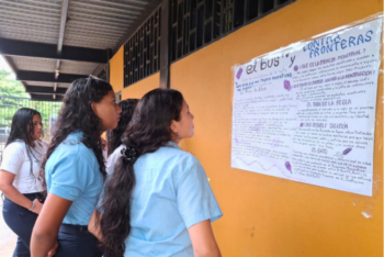 A group of young female students read an informative poster on the wall.