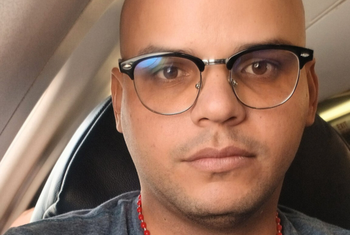 Cuban journalist José Luis Tan seated on a plane seat.