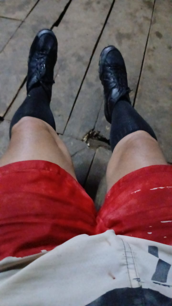 Image of the lower half of the body of Cuban journalist José Luis Tan wearing red shorts, black shoes and black socks.