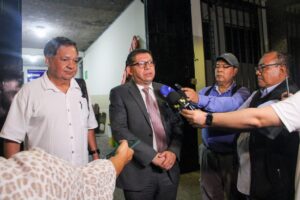 Two men speaking to journalists holding microphones