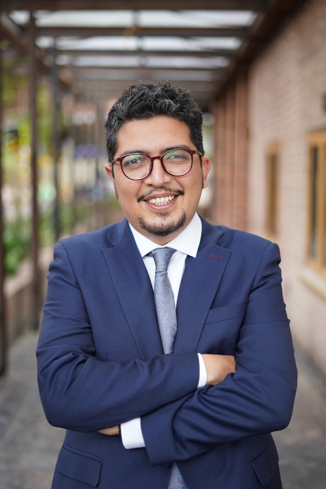 Hombre vestido de traje azul sonriendo y mirando a la cámara