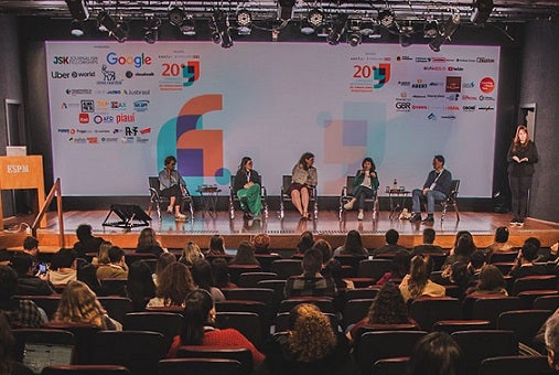 Panel discussion at the International Congress of Investigative Journalism hosted by Abraji in São Paulo, featuring five speakers on stage discussing AI's role in journalism, with audience members seated in red theater chairs facing the stage.
