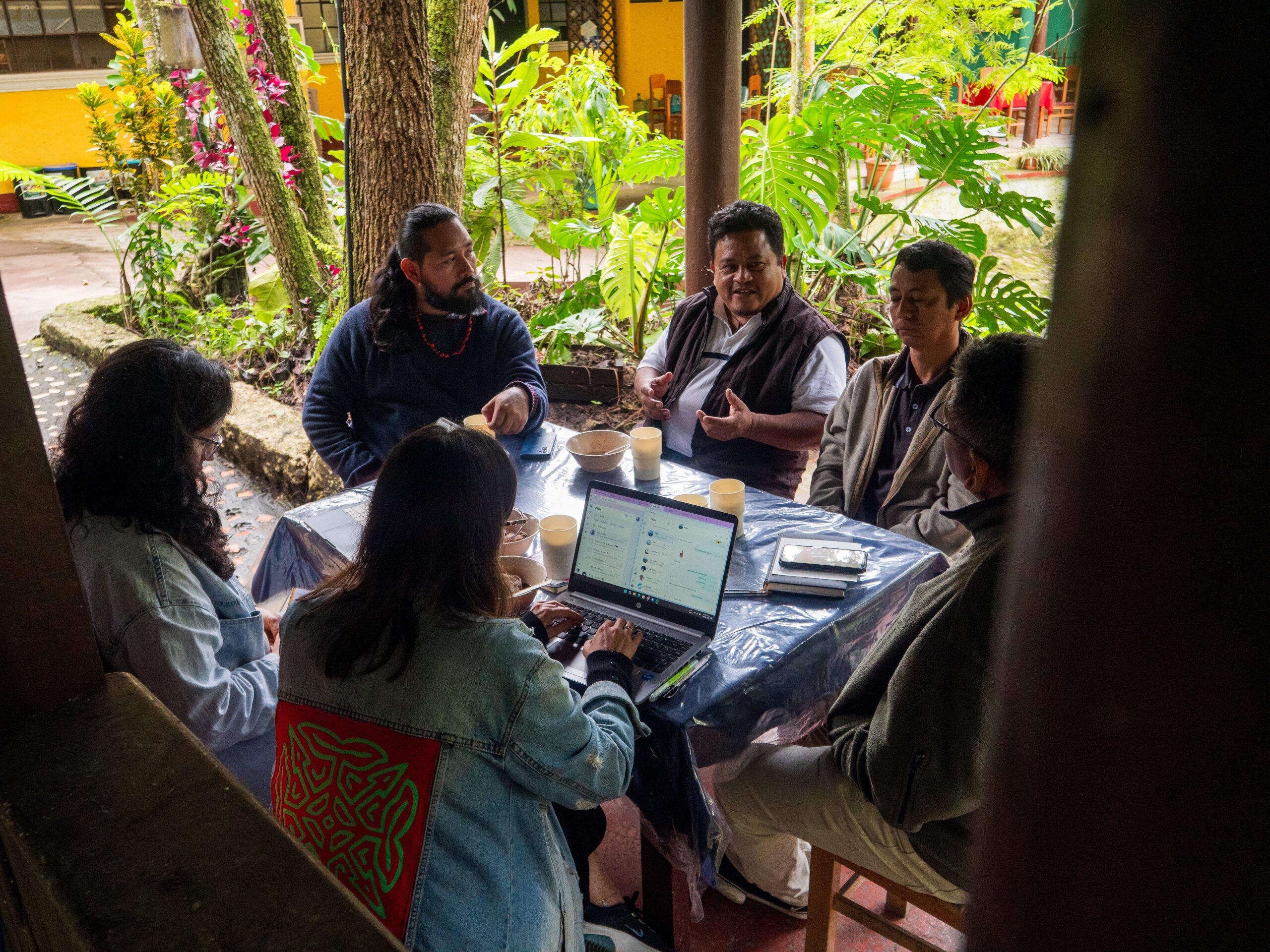 Dos investigadores hablan con cuatro periodistas comunitarios alrededor de una mesa.