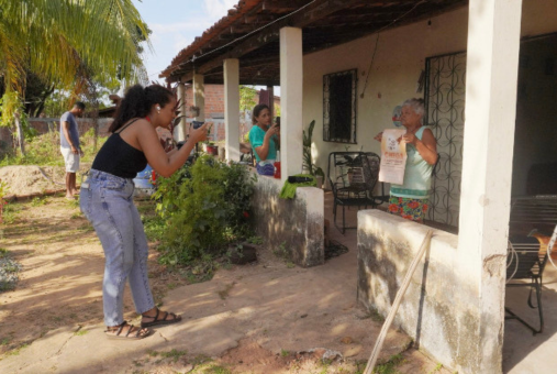 Journalist with camera takes photo of person holding a poster