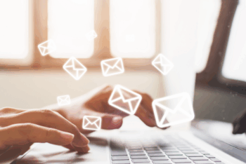 Hands typing on a laptop with email symbols, symbolizing newsletter distribution.