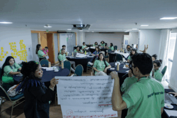 Two people holding a poster in front of group