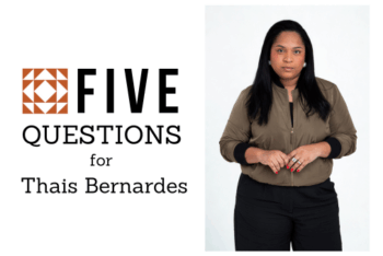 Portrait of journalist Thaís Bernardes standing against a plain white background. She faces the camera with a neutral expression, wearing a light brown bomber jacket and black pants, with her hands lightly clasped in front of her. Next to her, the graphic reads “Cinco Perguntas para Thais Bernardes” with the LJR logo.