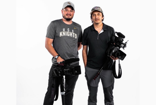 Two men smiling holding video cameras looking at the camera
