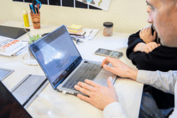 Two people typing on a laptop
