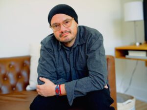 Young man seating in a chair, looking at the camera 