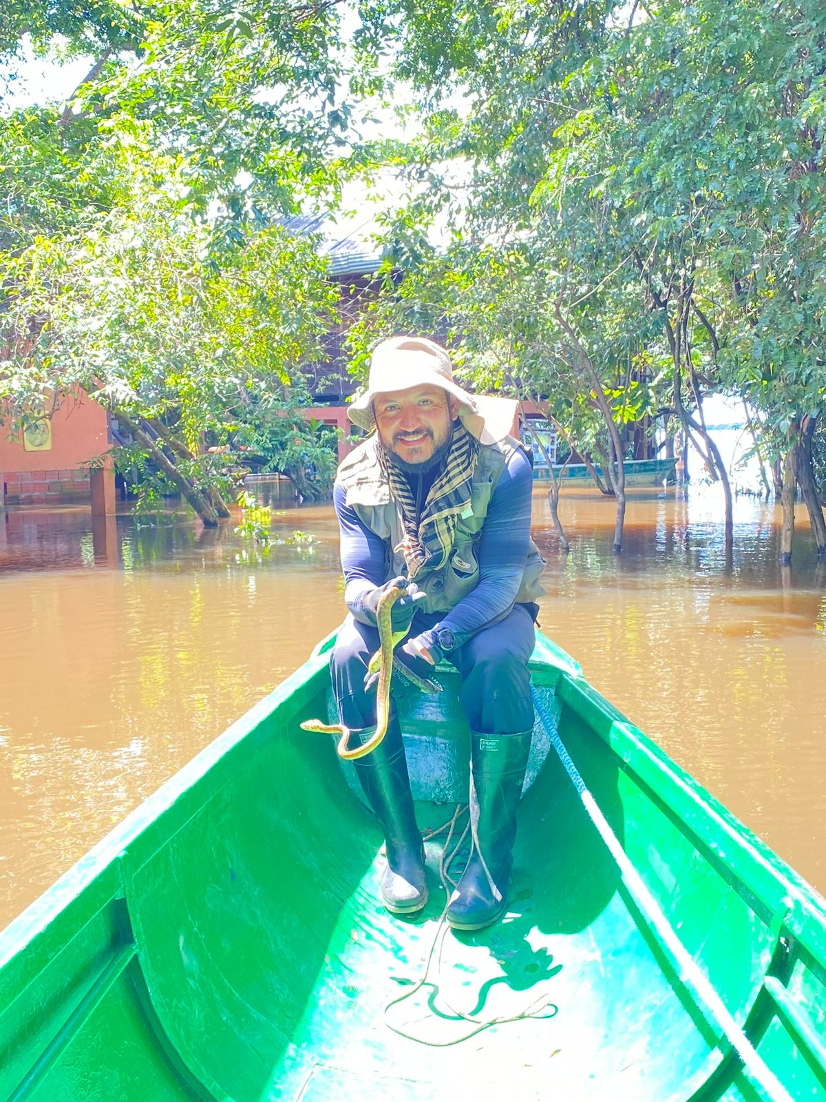 Man in a small canoe holding a snake