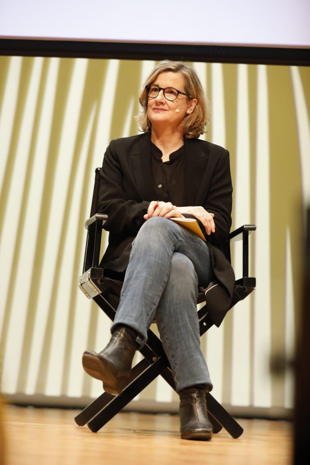 Spanish journalist Carmela Ríos sitting on a chair on a stage during a panel.