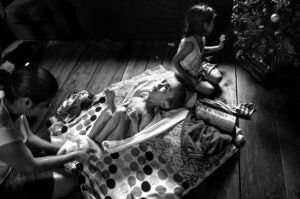 Using a towel, a woman dries the feet of her son who has hydrocephalus